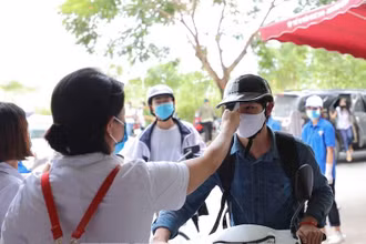 Cán bộ y tế kiêm tra thân nhiệt của thí sinh tham dự Kỳ thi tốt nghiệp THPT 2020 tại Điểm thi Trường THCS Nam Từ Liêm (Cầu Giấy, Hà Nội) chiều 8-8 (Ảnh: THANH TÙNG)
