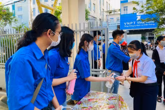 Thanh niên tình nguyện đo thân nhiệt học sinh trước khi vào điểm thi.