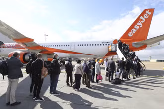 Hành khách chuẩn bị lên máy bay khởi hành từ sân bay Gatwick, Anh, tới Bồ Đào Nha, ngày 17-5. (Ảnh: AP)
