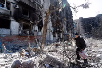 Người đàn ông đi qua sân của một tòa chung cư tại TP Mariupol, Ukraine, ngày 28/3. (Ảnh: Reuters)
