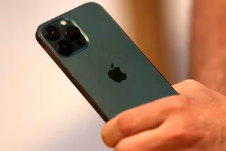 Một khách hàng cầm trên tay chiếc điện thoại iPhone 13 Pro màu xanh lục mới ngay sau khi nó được bày bán bên trong Apple Store tại Đại lộ số 5 ở Manhattan, New York City, tiểu bang New York, Mỹ, ngày 18/3/2022. (Ảnh: Reuters)