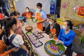 Khách tham quan thích thú thưởng thức bánh dân gian tại lễ hội.