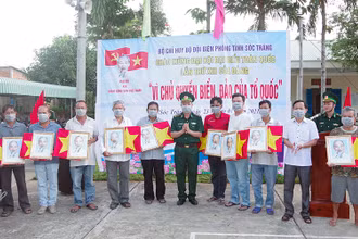 Đại tá Lê Văn Anh, Phó chính uỷ, BĐBP tỉnh trao cờ tổ quốc và ảnh Bác Hồ cho ngư dân.