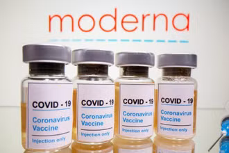 Lọ vaccine Covid-19 được đặt phía trước biểu trưng Moderna được chụp vào ngày 31-10-2020. Ảnh: Reuters.