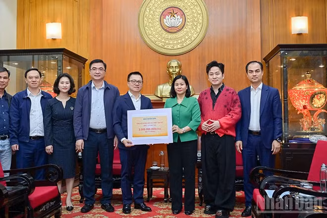 Tổng Biên tập Báo Nhân Dân Lê Quốc Minh trao kinh phí ủng hộ đồng bào khắc phục hậu quả bão, lũ. (Ảnh: BẢO LONG)