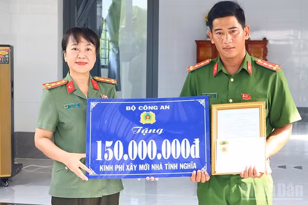 Đại tá Võ Thị Hoài Ngọc, Phó Giám đốc Công an tỉnh Đồng Tháp trao bảng tượng trưng kinh phí xây mới nhà tình nghĩa do Bộ Công an hỗ trợ tặng Đại úy Trần Minh Giàu. (Ảnh: PHƯỚC THANH)