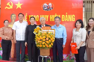 Bí thư Tỉnh ủy Đồng Tháp Ngô Chí Cường (thứ 3 từ phải qua) trao Huy hiệu Đảng và tặng hoa chúc mừng đồng chí Huỳnh Minh Đoàn. (Ảnh: Hữu Nghĩa)