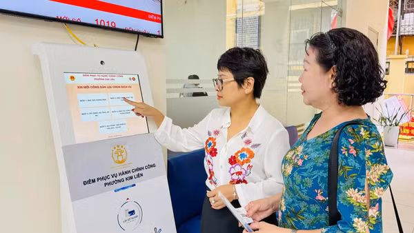 Công chức tại Điểm tiếp nhận, phục vụ hành chính công phường Kim Liên hướng dẫn người dân lấy số để thực hiện các thủ tục hành chính. (Ảnh: KHÁNH HUY)