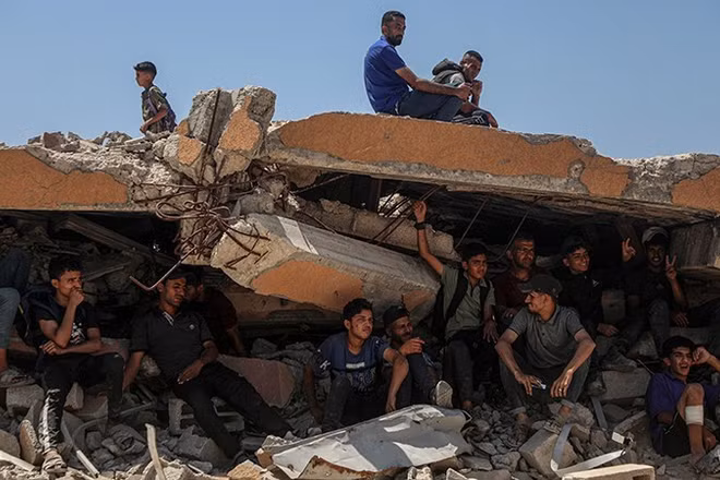 Người dân Palestine ngồi trên đống đổ nát ở khu vực Sudaniya, phía bắc thành phố Gaza. (Ảnh: Tân Hoa Xã/TTXVN) 