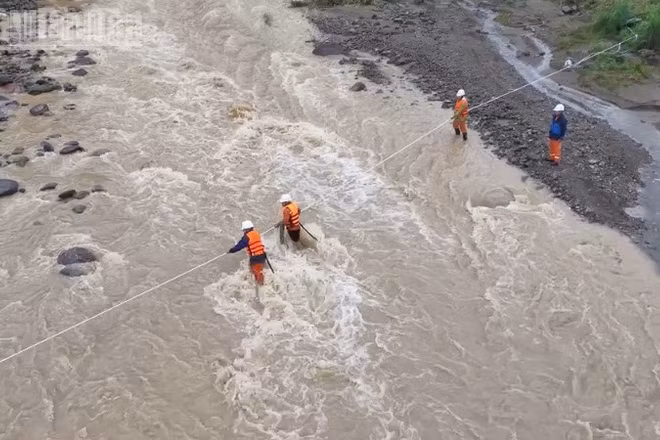 Cán bộ nhân viên Điện lực khu vực Mường La giăng dây vượt suối đến khu vực xảy ra sự cố về điện tại bản Hua Nặm, xã Mường La để khôi phục việc cấp điện.
