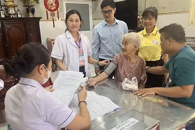 “Đội phản ứng nhanh” phường Minh Phụng (Thành phố Hồ Chí Minh) khám sức khỏe tại nhà cho bà Lê Thị Đời - 81 tuổi, đối tượng yếu thế. (Ảnh: MINH ANH)