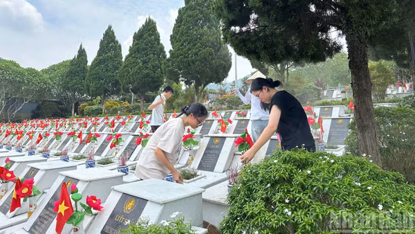 Các em học sinh dọn vệ sinh tại Nghĩa trang Liệt sĩ Vị Xuyên.