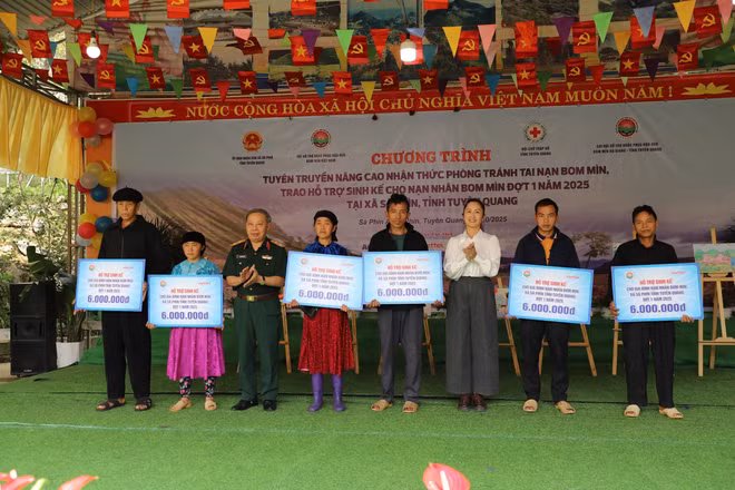 Trung tướng Phạm Ngọc Khóa, Phó Chủ tịch thường trực Hội Hỗ trợ khắc phục hậu quả Bom mìn Việt Nam và đồng chí Lý Thị Kiên, Phó Bí thư thường trực xã Sà Phìn trao hỗ trợ. sinh kế cho gia đình các nạn nhân bom mìn.