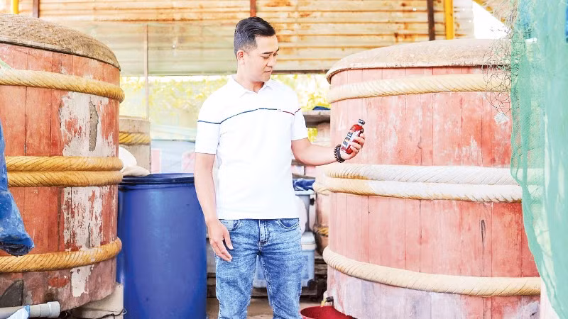 Anh Võ Nguyên Tùng, Trưởng ban làng nghề truyền thống nước mắm Cửa Khe, bên những thùng gỗ ủ mắm của mình.
