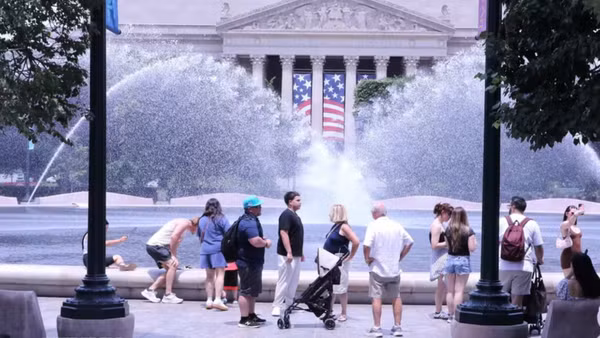 Du khách tránh nắng nóng bên đài phun nước tại khu vực National Mall (Quảng trường Quốc gia) ở thủ đô Washington D.C. (Ảnh: TTXVN)