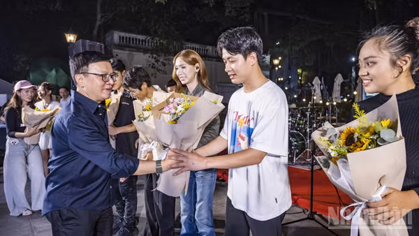 Tổng Biên tập Báo Nhân Dân Lê Quốc Minh tặng hoa cho các ca sĩ biểu diễn tại chương trình. (Ảnh: THÀNH ĐẠT)