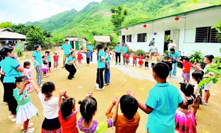 Các thành viên dự án “Đông ấm cho trẻ em vùng cao” cùng học sinh điểm trường Pa Phang 2, Trường mầm non Phìn Hồ (huyện Sìn Hồ, Lai Châu) bên hai lớp học mới khánh thành dịp Quốc tế Thiếu nhi. (Ảnh: PHONG CHƯƠNG)