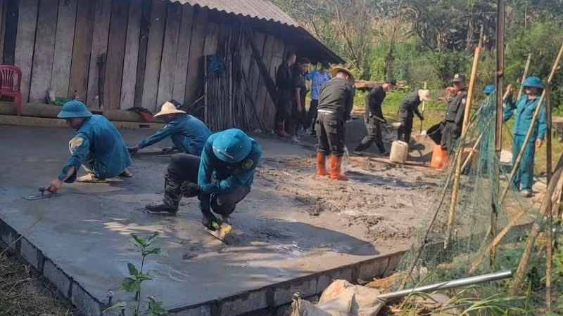 Công an và dân quân tự vệ hỗ trợ đổ bê tông nền nhà cho hộ nghèo ở xã Hiệp Lực. (Ảnh: THÀNH TÂM)