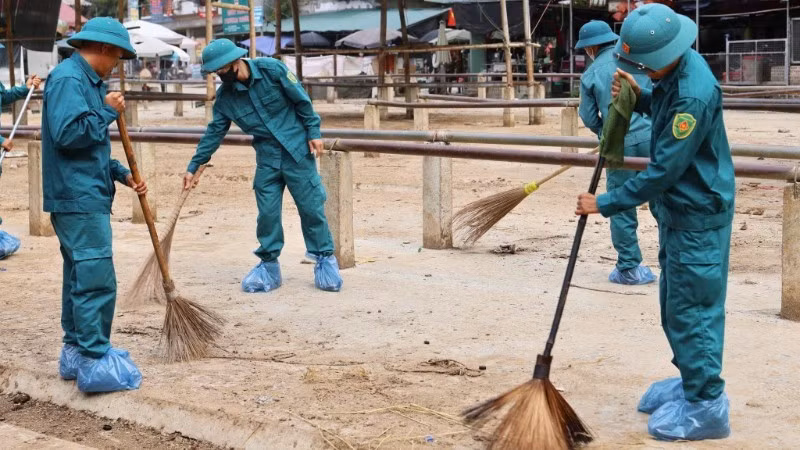 Lực lượng dân quân tự vệ vệ sinh môi trường tại chợ. (Ảnh: Xã Nghiên Loan)