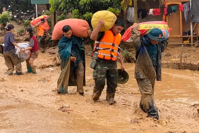 Lực lượng cứu hộ di chuyển tài sản giúp người dân vùng lũ đến nơi an toàn.
