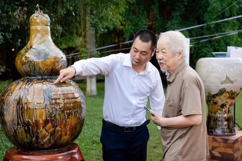 Ông Vũ Đình Mạnh (bên trái) giới thiệu tác phẩm cho khách tham quan.