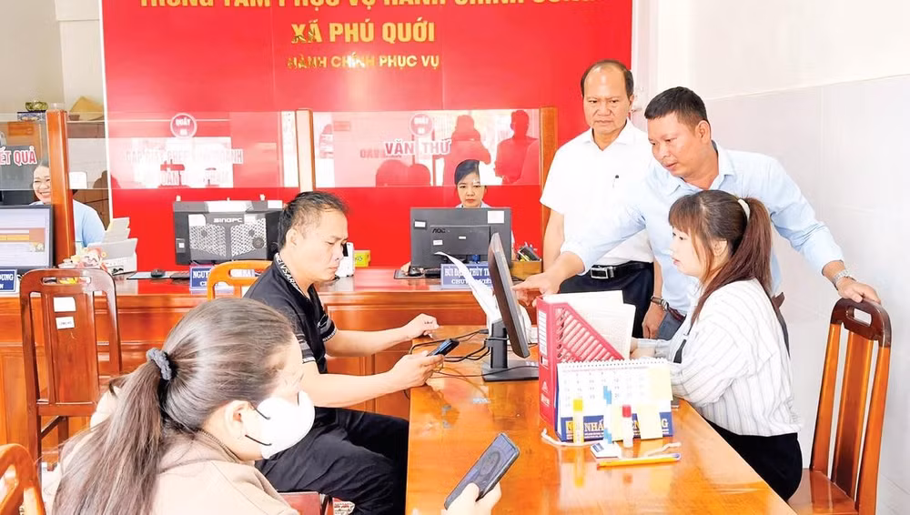 Cán bộ Trung tâm Phục vụ hành chính công xã Phú Quới hướng dẫn người dân làm thủ tục hành chính. 