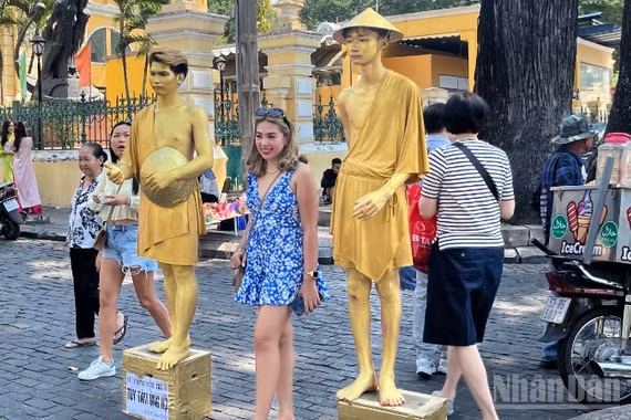 Du khách nước ngoài chụp ảnh lưu niệm tại khu vực trước Bưu điện trung tâm Thành phố. (Ảnh: LINH BẢO)