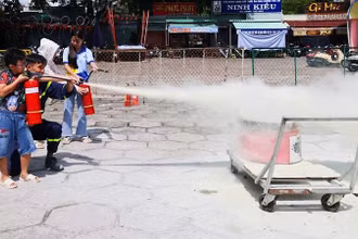 Các em thiếu nhi thực hành dùng bình chữa cháy dập lửa tại buổi tập huấn.
