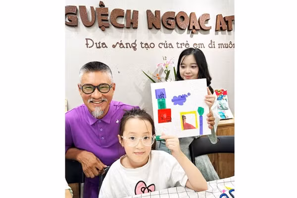 Họa sĩ Đào Hải Phong bên cạnh cháu Linh Chi (5 tuổi) với tác phẩm vui của cháu, cắt ảnh của họa sĩ dán vào tranh để tô vẽ.
