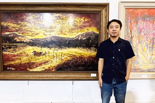 Họa sĩ Nguyễn Bỉnh Sơn bên tác phẩm của mình.