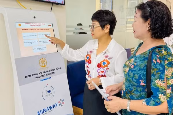 Công chức tại Điểm tiếp nhận, phục vụ hành chính công phường Kim Liên hướng dẫn người dân lấy số để thực hiện các thủ tục hành chính. (Ảnh: KHÁNH HUY)