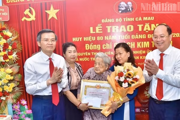 Đồng chí Đoàn Minh Huấn, Ủy viên Bộ Chính trị, Giám đốc Học viện Chính trị quốc gia Hồ Chí Minh (bên trái) và đồng chí Nguyễn Hồ Hải, Bí thư Tỉnh ủy Cà Mau (bên phải) trao Huy hiệu 80 năm tuổi Đảng tặng đồng chí Quách Kim Tuyến, ở phường Bạc Liêu, tỉnh Cà Mau. (Ảnh: PV)