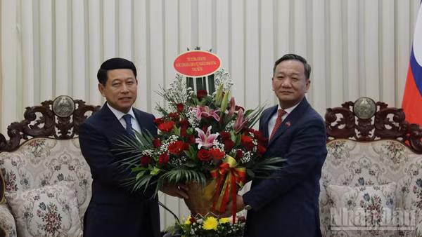 Đại sứ Nguyễn Minh Tâm chuyển lẵng hoa của Thủ tướng Lê Minh Hưng chúc mừng Thủ tướng Lào Saleumxay Kommasith. (Ảnh: DUY TOÀN)