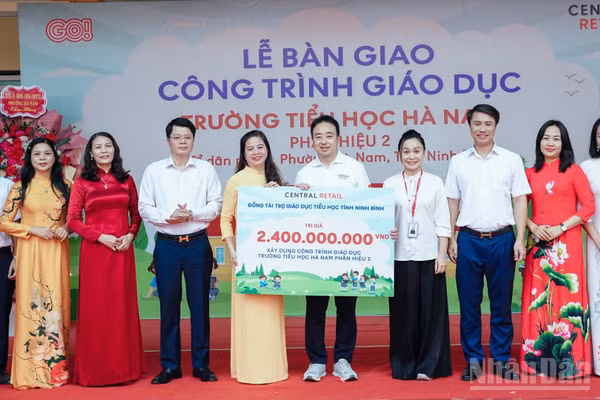 Các đại biểu thực hiện nghi thức trao bảng tài trợ tượng trưng cho nhà trường. (Ảnh: TÂN VŨ)