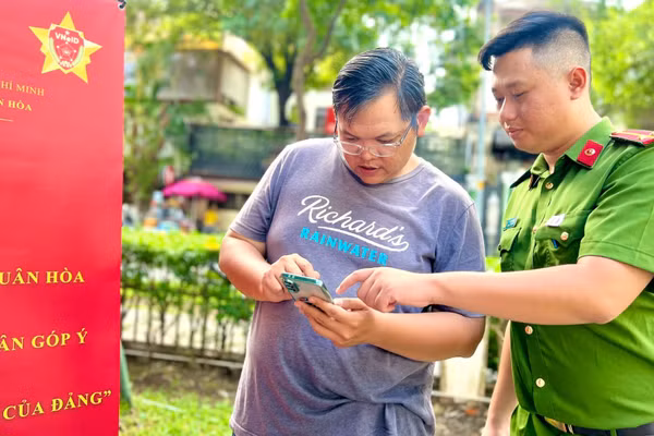 Công an phường Xuân Hòa hướng dẫn người dân thao tác các tiện ích trên ứng dụng VNeID. (Ảnh: QUANG QUÝ)