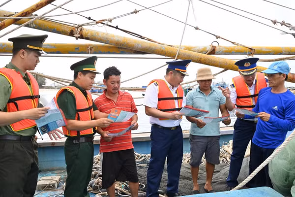 Cảnh sát biển và các lực lượng chức năng phát tờ rơi tuyên truyền phòng, chống IUU cho ngư dân. (Ảnh: Cảnh sát biển cung cấp)