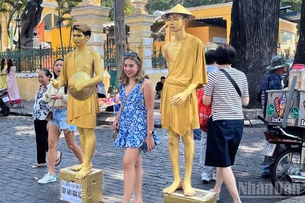 Du khách nước ngoài chụp ảnh lưu niệm tại khu vực trước Bưu điện trung tâm Thành phố. (Ảnh: LINH BẢO)
