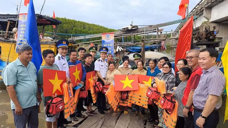 Đại diện Bộ Tư lệnh Vùng Cảnh sát biển 3 và Ban Tuyên giáo và Dân vận Tỉnh ủy Vĩnh Long tặng cờ Tổ quốc, áo phao, túi thuốc y tế... cho ngư dân.