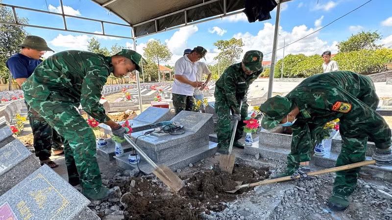 Cán bộ, chiến sĩ Đồn Biên phòng Cửa khẩu cảng Giao Long thực hiện việc cất bốc, quy tập hài cốt liệt sĩ chưa xác định danh tính. (Ảnh: HOÀNG TRUNG)