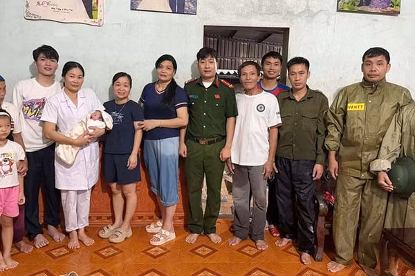 Lực lượng chức năng cùng gia đình vui đón trẻ sơ sinh trong mưa lũ. (Ảnh: Công an Thanh Hóa)