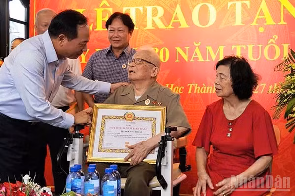 Đồng chí Trưởng Ban Tuyên giáo Trung ương trao Huy hiệu 80 năm tuổi Đảng cho cụ Trịnh Khắc Thuần. (Ảnh: MAI LUẬN)