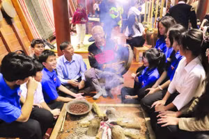 Già làng người Ê Đê ngồi kể chuyện về văn hóa cồng chiêng cho các cháu học sinh bên bếp lửa trong ngôi nhà dài truyền thống.