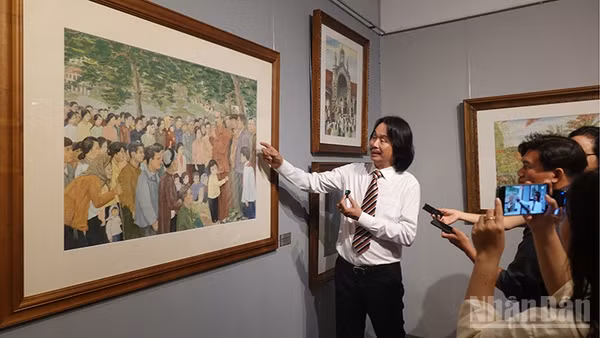 Họa sĩ Văn Đức, con trai họa sĩ Văn Giáo giới thiệu với công chúng bức tranh Bác Hồ thăm nhân dân Hà Bắc (1978). (Ảnh: LINH BẢO)