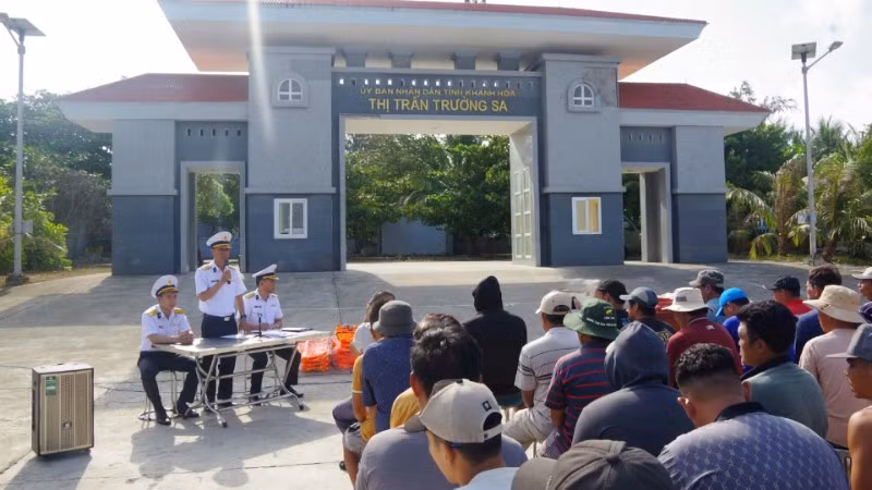 Cán bộ Trung tâm Dịch vụ hậu cần kỹ thuật Trường Sa tuyên truyền, phổ biến cho ngư dân về Chỉ thị 45 và về hoạt động của các âu tàu, làng chài trên quần đảo Trường Sa. (Ảnh: Đức Thuận)