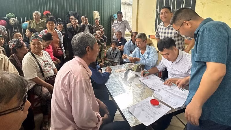Cán bộ văn phòng Công ty cổ phần Cao-su Điện Biên chi trả tiền góp đất đến người dân trên địa bàn xã Mường Pồn, tỉnh Điện Biên.