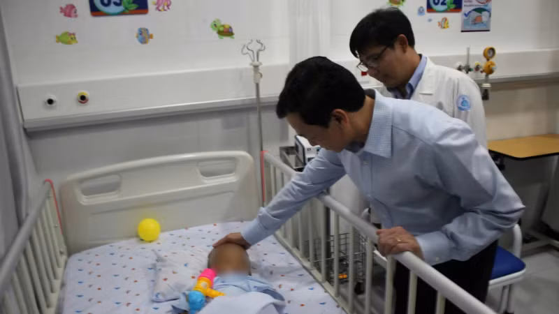 Thứ trưởng Bộ Y tế Nguyễn Tri Thức thăm cháu bé bị bạo hành tại Bệnh viện Nhi đồng 1, Thành phố Hồ Chí Minh. (Ảnh: ĐỖ BÁ)