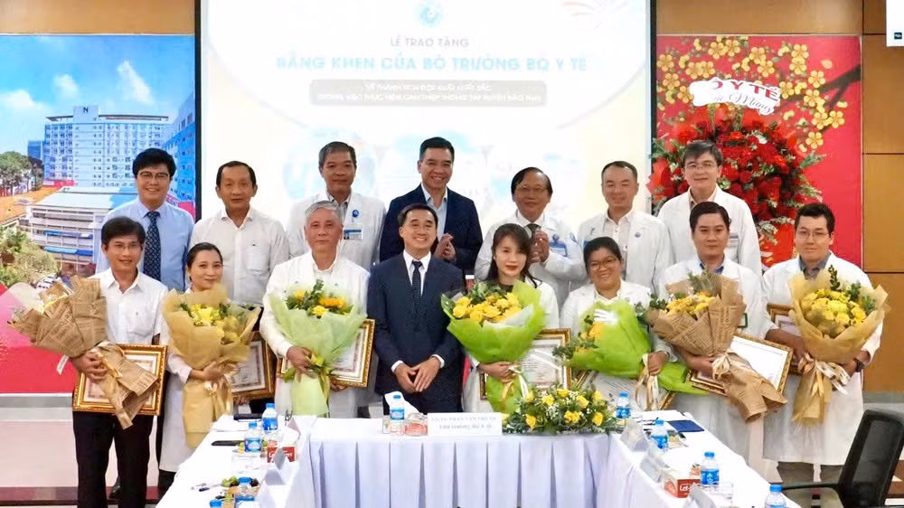 Thứ trưởng Y tế Trần Văn Thuấn tặng hoa và bằng khen cho ekip thực hiện ca can thiệp bào thai cho sản phụ người Singapore. (Ảnh: HOÀNG HÙNG)