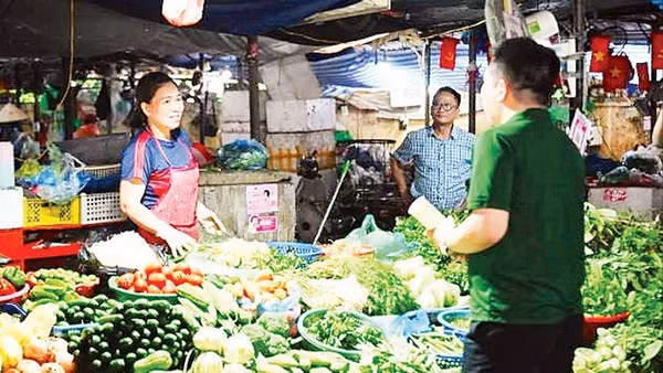 Tiểu thương tại chợ Đồng Xa (Hà Nội) được nhân viên VPBank hướng dẫn mở tài khoản hộ kinh doanh ngay tại quầy hàng. (Ảnh: MAI HẠ)