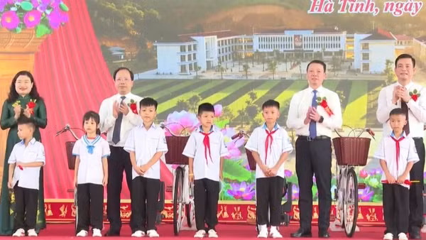 Các đồng chí lãnh đạo tỉnh Hà Tĩnh tặng quà các em học sinh nghèo vượt khó tại Lễ khánh thành Trường phổ thông nội trú tiểu học và trung học cơ sở Sơn Kim 1. (Ảnh: NT)