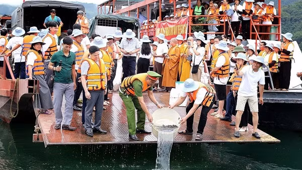 Cán bộ, nhân dân phường Thống Nhất cùng tăng ni, phật tử thả cá giống xuống tại lòng hồ Hòa Bình.